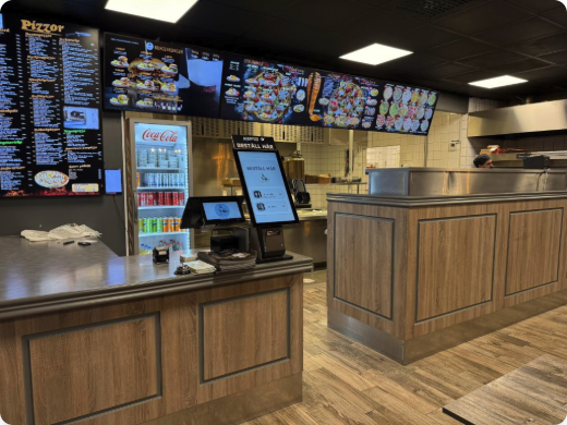 Kassadisk i en pizzeria med digitala menyskärmar